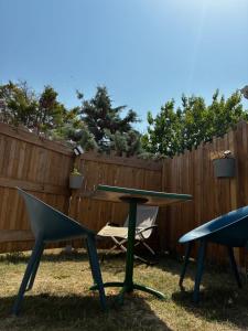 a picnic table and chairs in front of a fence at Appartement Talmont sur Gironde in Talmont