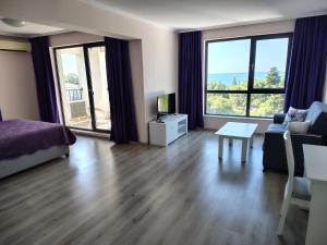 a living room with a bed and a couch and a table at Апартамент Ивела in Balchik