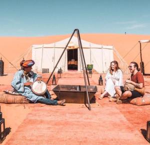 a group of people sitting in the desert at Authentic Luxury Camp in Merzouga