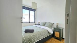 a white bedroom with a bed and a window at 3star 1950s house, 3 bedrooms, 6 people, walk to beach center in Royan