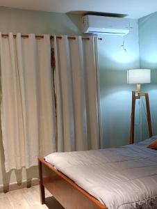 a bedroom with a bed with curtains and a lamp at Casa costa oeste in Posadas