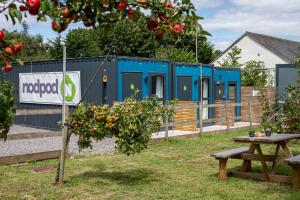 布里斯托nodpod accommodation的一座蓝色的建筑，里面有一张野餐桌和一棵苹果树