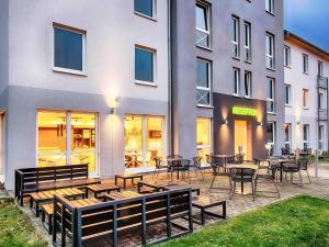 Un patio con mesas y sillas frente a un edificio. en B&B Hotel Kassel-Süd, en Kassel