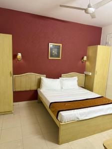 Un dormitorio con una cama con una pared roja. en Western e-Inn, en Bangalore