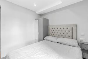 a white bedroom with a bed and a headboard at Ensuite Double Godino Hotel by Ilford Station in Ilford