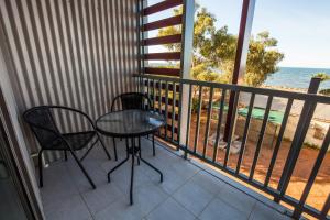 
a patio area with chairs, a table and a balcony at Beadon Bay Hotel in Onslow
