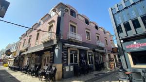 un bâtiment rose avec des tables et des chaises dans une rue dans l'établissement Blue Beach Home with Terrace, à Albufeira