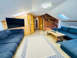 Una sala de estar con un sofá azul y una mesa. en Vila Eruga- Apartament 2, en Poiana Mărului