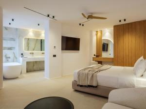 a bedroom with a bed and a tub and a sink at Panormos Bay Collection Mykonos in Panormos Mykonos