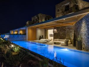 a villa with a swimming pool at night at Panormos Bay Collection Mykonos in Panormos Mykonos