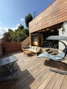 un patio con sillas y un sofá en una terraza de madera en Cosy Room & SAUNA Hypercentre Dieppe, en Dieppe