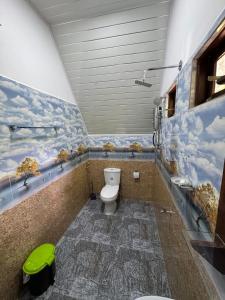 a bathroom with a toilet with a painting on the wall at Lake Wind in Habarana