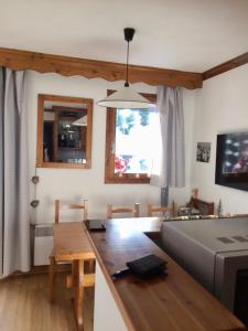 a kitchen and living room with a table and a couch at Valmorel Appartement au pied des pistes in Valmorel +4 photos