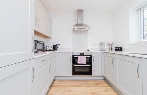 a white kitchen with white cabinets and a stove at Stylish 3 Bedroom Home Perfect for Families in Bicester +7 photos