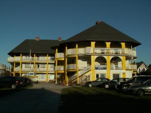 a large yellow building with cars parked in a parking lot at Pod Złotym Żaglem in Karwia