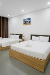 two beds in a hotel room with white walls at Đảo Ngọc Homestay - Grand World Phú Quốc in Phu Quoc
