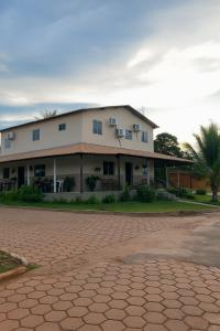 a large white building with a palm tree in front of it at Pousada Alma Jalapoeira - Mateiros in Mateiros