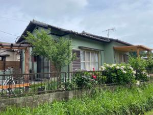 a green house with flowers on a fence at 田辺ハウス in Kafuri