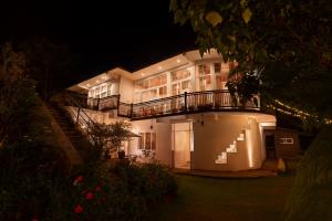 a large white building with a balcony at night at The Ceylon Lodge in Nuwara Eliya