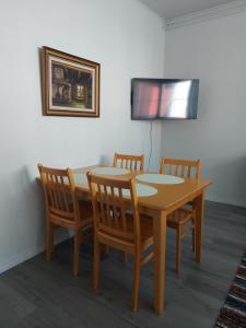 a dining room table with four chairs and a television at Huoneisto Katu in Kokkola +3 photos