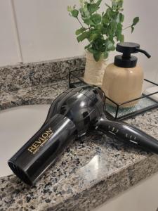 a blow dryer sitting on a counter in a bathroom at Studio novo com ambiente acolhedor in São João del Rei