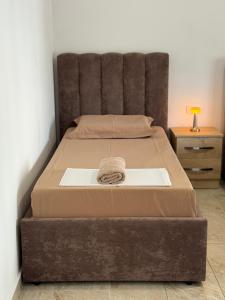 a large bed with a brown headboard and a table at Bejart Apartment 7 in Tirana
