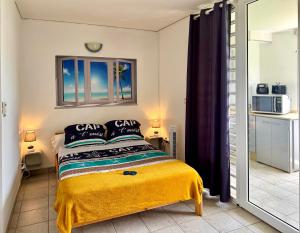 a bedroom with a bed with a yellow blanket at Marina Sun Tropic in Le Marin