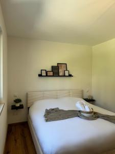 a bedroom with a white bed with a shelf on the wall at Neubau, Bergpanorama, gute Lage, Tiefgarage in Berchtesgaden