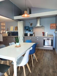 una cucina con un tavolo bianco e sedie blu di La Cabane des Mouts- Piscine -Clim a Vendres-Plage