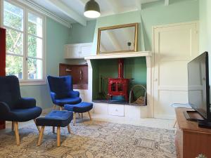 a living room with a fireplace with two chairs and a tv at La Cabane des Mouts- Piscine -Clim in Fleury