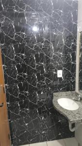 a bathroom with a sink and a black marble wall at Rio Quente Thermas Paradise in Rio Quente