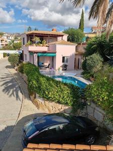 a car parked in front of a house with a swimming pool at Pink Villa in Peyia
