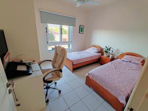 a bedroom with two beds and a desk and a chair at Pink Villa in Peyia