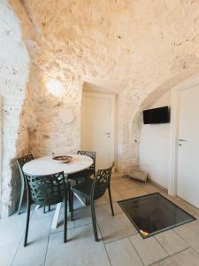 Una mesa y sillas en una habitación con una pared de piedra. en Da Memela Trulli e Lamie per vacanze da sogno in Puglia, en Martina Franca 17 fotos más