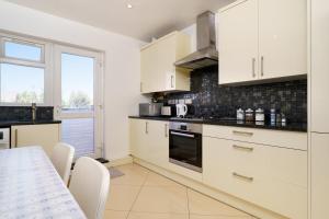 a kitchen with white cabinets and a table at 2BR Apartment near Heathrow Airport in Harmondsworth