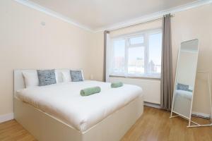 a white bedroom with a large bed and a window at 2BR Apartment near Heathrow Airport in Harmondsworth