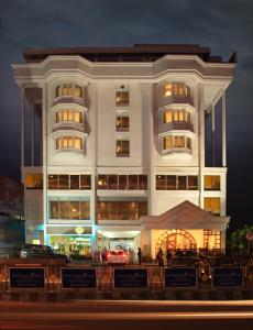 a large white building with cars parked in front of it at Hotel Abad Plaza in Cochin