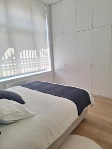 une chambre avec un lit avec des armoires blanches et une fenêtre dans l'établissement Louise Luxe Stay in Central Brussels, à Bruxelles