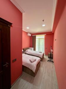 two beds in a room with red walls at Khidikari Hotel in Ambrolauri