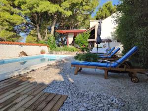 a couple of chairs and an umbrella next to a pool at Vacation house Milka in Milna