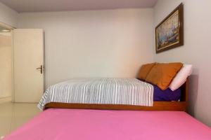 a small bedroom with a bed with a pink blanket at Sejahtera Apartment in Jogja 3bedrooms in Kejayan