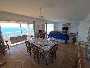un salon avec une table et des chaises et l'océan dans l'établissement Villa Saint-Michel, à Galéria 46 autres photos