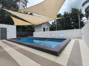 a swimming pool with two chairs and a large umbrella at Mar'wanis Villa Homestay Beaufort Sabah in Bambangan
