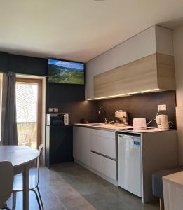 a kitchen with a table and a tv on the wall at Hacienda Dedinky B in Dedinky