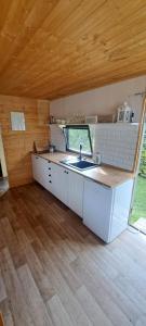 a kitchen with a sink and a wooden ceiling at Rozkoš beach mobilheim in Velká Jesenice
