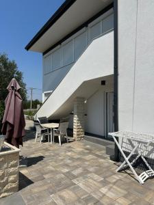 a patio with tables and chairs next to a building at Apartment Oblak in Vrsi