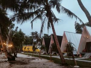 a group of palm trees in front of a building at Krui Ocean Cottage BV in Krui