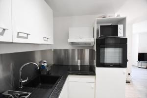 a kitchen with a sink and a microwave at Le Petit Cocon in Château-Chinon