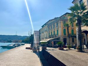 a street with buildings and palm trees next to a river at Victoria Palace in Salò