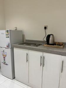a kitchen with white cabinets and a white refrigerator at شقة بصالة جلوس وغرفه نوم in Al Kharj